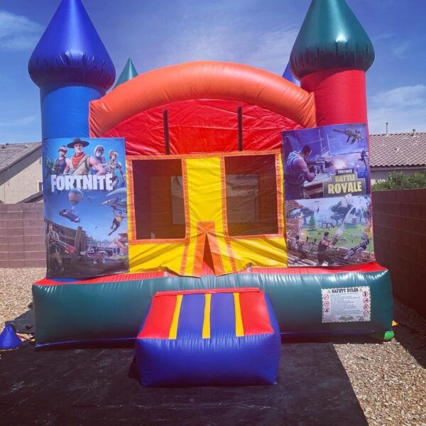 Colorful Fortnite-themed bounce house with slides and towers, set up outdoors.