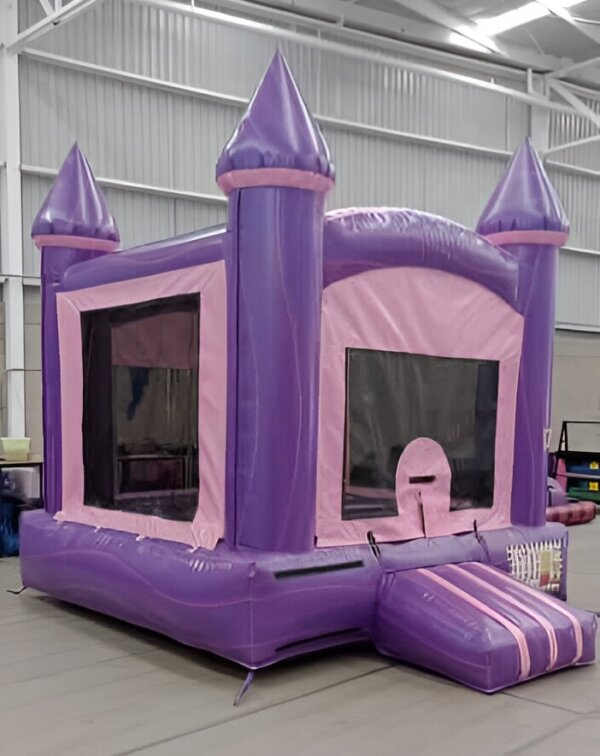 Inflatable purple and pink bounce castle jumper with turrets, indoors.